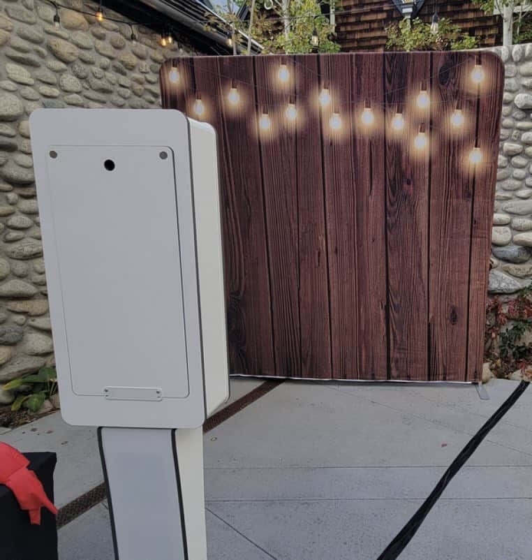 DJ booth with wooden backdrop and string lights for outdoor events.